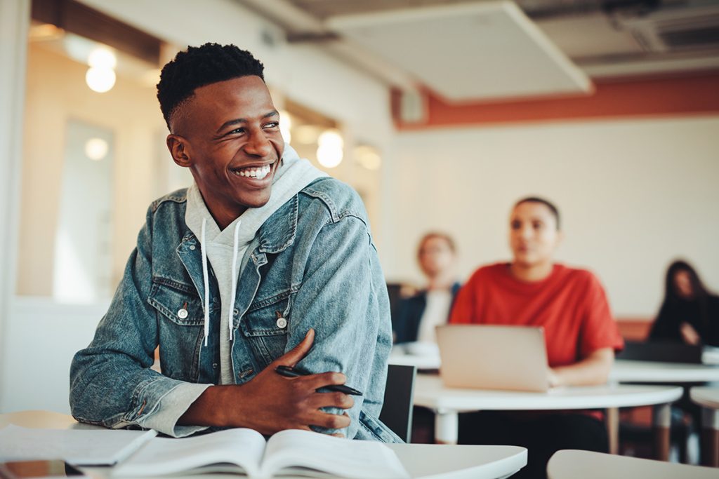 student_smiling_web African American male student laughing while sitting at his desk.